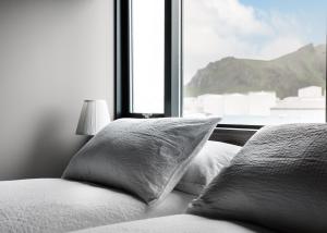a bed with two pillows in front of a window at Pier Apartments in Vestmannaeyjar