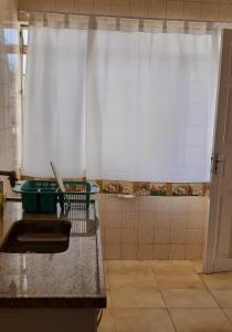 uma cozinha com uma cortina branca e um chuveiro em Apartamento no centro em São Lourenço