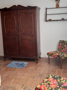 a living room with a large wooden cabinet and a chair at Apartamento no centro in São Lourenço