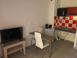 - une petite cuisine avec une table et une télévision dans la chambre dans l'établissement Studio Residence Cote Green, à Montpellier