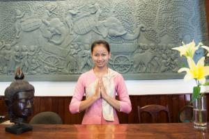 Una donna in piedi davanti a un tavolo con una statua. di Reaksmey Chanreas Hotel a Siem Reap