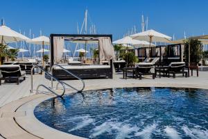 a swimming pool in a resort with tables and umbrellas at Marina di Scarlino Resort in Puntone di Scarlino