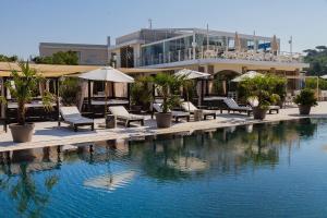 a pool with chairs and umbrellas next to a building at Marina di Scarlino Resort in Puntone di Scarlino