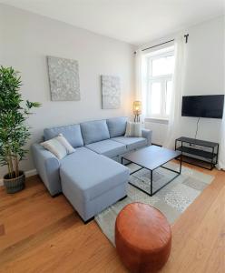 DOWA Apartments Thaliastrasse في فيينا: غرفة معيشة مع أريكة زرقاء وطاولة