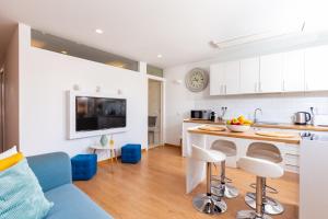 een keuken en een woonkamer met witte kasten en een blauwe bank bij Yumbo Teror Two Bedroom Apartment in Playa del Inglés