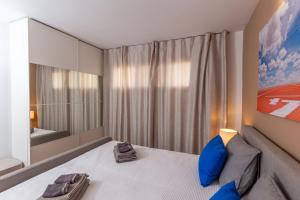 een slaapkamer met een bed met blauwe kussens en een spiegel bij Yumbo Teror Two Bedroom Apartment in Playa del Inglés