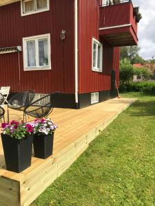 a wooden deck in front of a red house with flowers at Säfsen in Fredriksberg