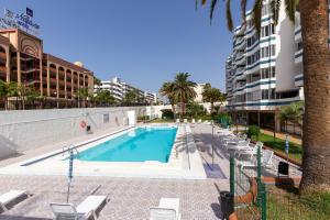 een zwembad met ligstoelen naast een gebouw bij Yumbo Teror Two Bedroom Apartment in Playa del Inglés