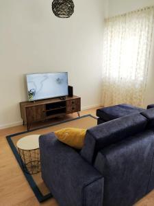 a living room with a blue couch and a flat screen tv at Portela House - T3 Residential home 50 meters from the beach in Vila Praia de Âncora