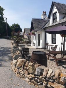 a stone retaining wall in front of a house at Ardeonaig Hotel & Restaurant in Ardeonaig