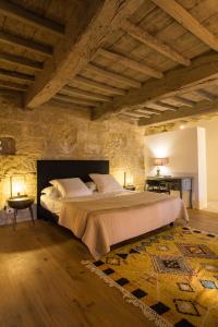 a bedroom with a large bed in a stone wall at La Maison D'Aimé in Saint-Quentin-la-Poterie