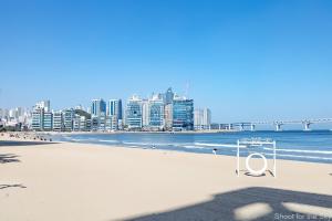een strand met een stoel op het zand en een stad bij Gwangan Stay Hotel in Busan