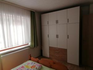 a bedroom with a bed and white cabinets and a window at Ferienwohnung Hain in Birnbaum