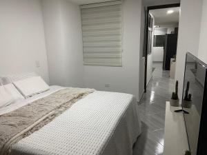 a white bedroom with a bed and a window at Aparta estudio Amoblado Sabaneta Colombia. Moderno, céntrico y cómodo. in Sabaneta