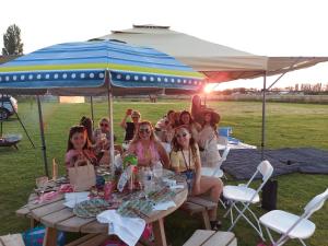 a group of women sitting at a table under an umbrella at Glamping with Llamas in Wisbech