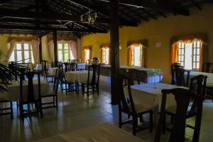 un comedor con mesas, sillas y ventanas en Hotel Itamaracá, en Miguel Pereira