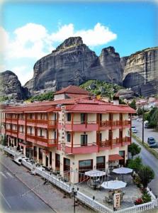 a large building with a mountain in the background at Famissi Hotel in Kalabaka