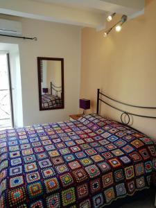 una camera da letto con un letto con un copriletto colorato e uno specchio di Alloggio Turistico Casa Vicolo Pincio a Grotte di Castro
