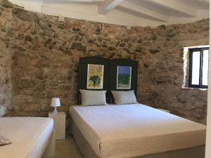 two beds in a room with a stone wall at Feudo Frammasi - Curte Glamping Experience in Salve