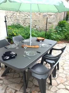 una mesa gris con sillas y una sombrilla en Maison solognote proche Chambord, en Saint Laurent Nouan