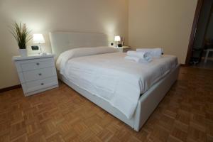 sypialnia z łóżkiem z białą pościelą i szafką nocną w obiekcie Residenza Feltre w Mediolanie