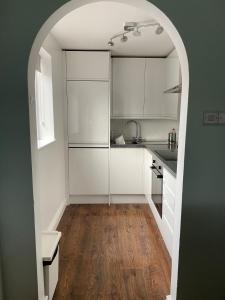 cocina con armarios blancos y suelo de madera en 15 Maple Court en Oxford