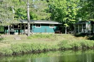 a blue house next to a body of water at Whole home, private lake, sauna, WFH office in Michigamme