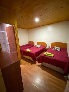 two beds in a room with red sheets at Hostería Estelita in Panimávida
