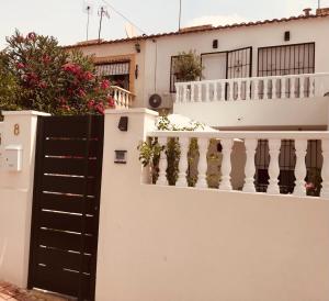 een wit huis met een zwarte poort en een balkon bij Apartamento Torrevieja in Torrevieja
