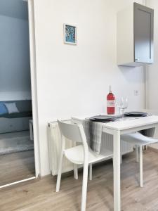 a white dining room table with two white chairs at Anita Apartman in Csopak
