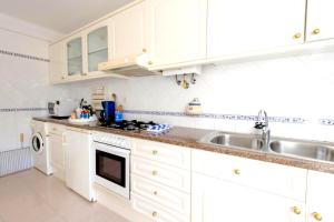 una cocina con armarios blancos y fregadero en Villa - Duna Parque Group, en Vila Nova de Milfontes