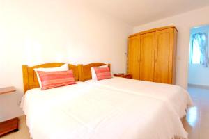 a bedroom with a large white bed with red pillows at Villa - Duna Parque Group in Vila Nova de Milfontes