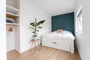 贊德沃特的住宿－The Shell Apartment，卧室配有白色的床和盆栽植物
