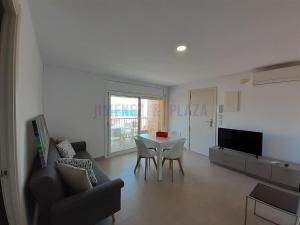 a living room with a table and a couch and a television at Apartamentos Dins Mar Apto. 7 in Torredembarra