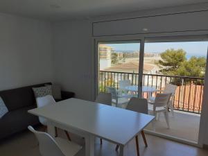 salon z białym stołem i krzesłami oraz balkonem w obiekcie Apartamentos Dins Mar Apto. 7 w mieście Torredembarra