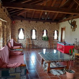 a living room with a table and a stone wall at Masia Del Aragones in Peñarroya de Tastavins