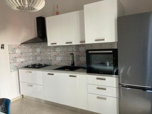La cuisine est équipée de placards blancs et d'un réfrigérateur en acier inoxydable. dans l'établissement Casa Etna Nicolosi, à Nicolosi