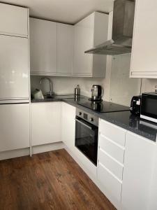 una cocina con armarios blancos y encimeras negras en 15 Maple Court en Oxford