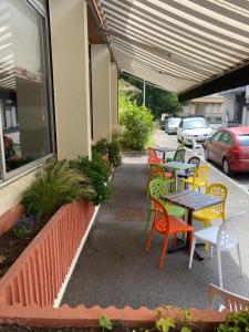 une terrasse avec des tables, des chaises et des voitures en stationnement dans l'établissement Hôtel des Pays Bas, à Lourdes