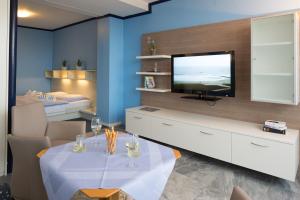 a living room with a television and a table with chairs at Hotels Haus Waterkant & Strandvilla Eils in Norderney