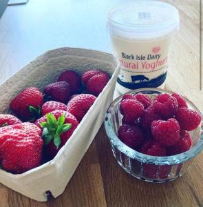 a basket of strawberries next to a container of yogurt at Friars Bridge Guesthouse in Inverness