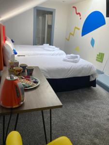 a hotel room with two beds and a table with a table at Friars Bridge Guesthouse in Inverness