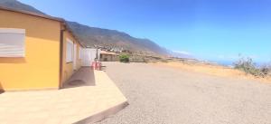 a building on a dirt road next to a mountain at Vista al Mar in Frontera