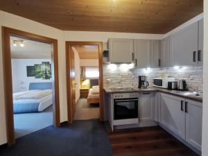 a kitchen with white cabinets and a room with a bed at Appartment Sonnenkogel in Holzgau