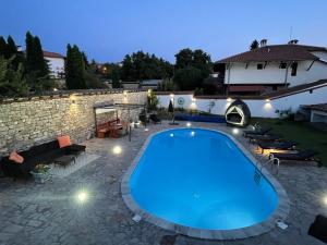 a swimming pool in a yard with a stone wall at Angliiska Vila in Arbanasi