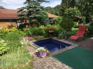 einen Pool in einem Garten mit einem Stuhl und Blumen in der Unterkunft Landhaus Renata Bayrischzell in Bayrischzell
