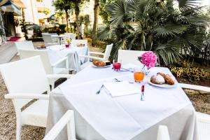 una mesa blanca con comida y flores. en New Hotel Chiari en Cervia