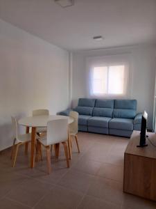 ein Wohnzimmer mit einem Sofa, einem Tisch und Stühlen in der Unterkunft Apartamento Blau Mar in Piles