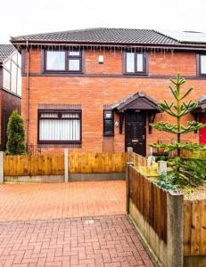 une maison en briques avec une clôture devant elle dans l'établissement BRIGSTOCK HOLIDAYS HOUSE, à Manchester