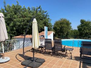 um pátio com 2 cadeiras, um guarda-sol e uma piscina em Casa do Meio- Farm house- Tavira em Tavira